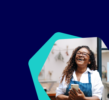 mulher em local de trabalho sorrindo com celular na mão